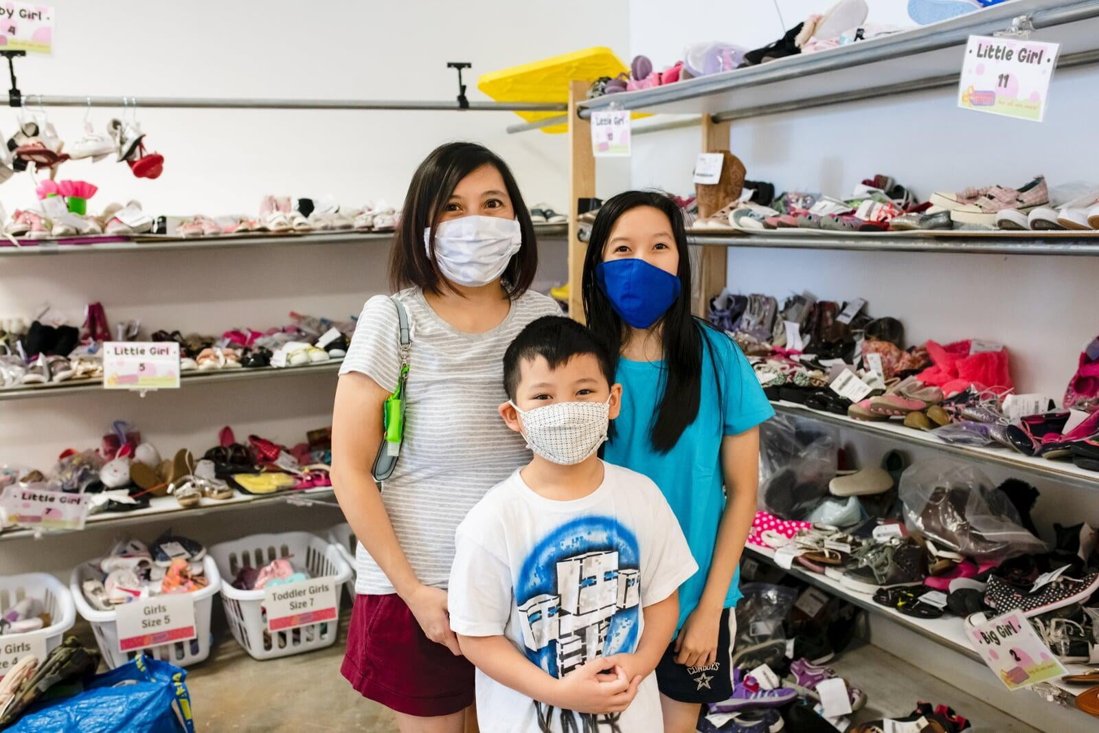 A mom and her two kids stand in the shoe section for a happy family photo.
